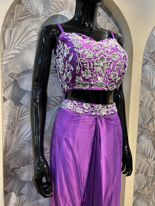 Purple silk crop top with white floral embroidery, paired with a draped silk skirt for party and festive wear
